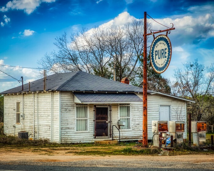 8×10 Color photo of an abandoned old gas station on a country road.