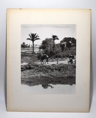 J.W. Howlett Black + white Photograph focusing on a Group of Travelers W/ Camel