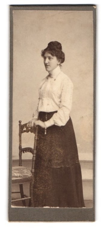 Photography Young Woman with Artful Hairstyle in Light Blouse and Dark Skirt