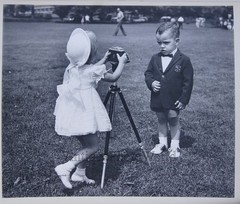 Children girl photographer w camera taking a photo of a boy vintage art photo
