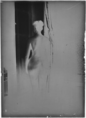Woman glass plate negative at window. Artistic nude. Circa 1900.