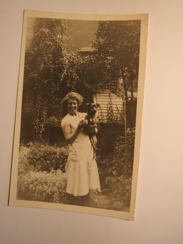 woman standing in garden with dog in arms / photo England